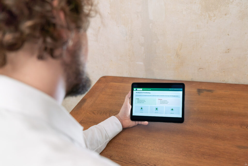 Benedict Krämer sitzt an einem Holztisch und arbeitet an einem Tablet