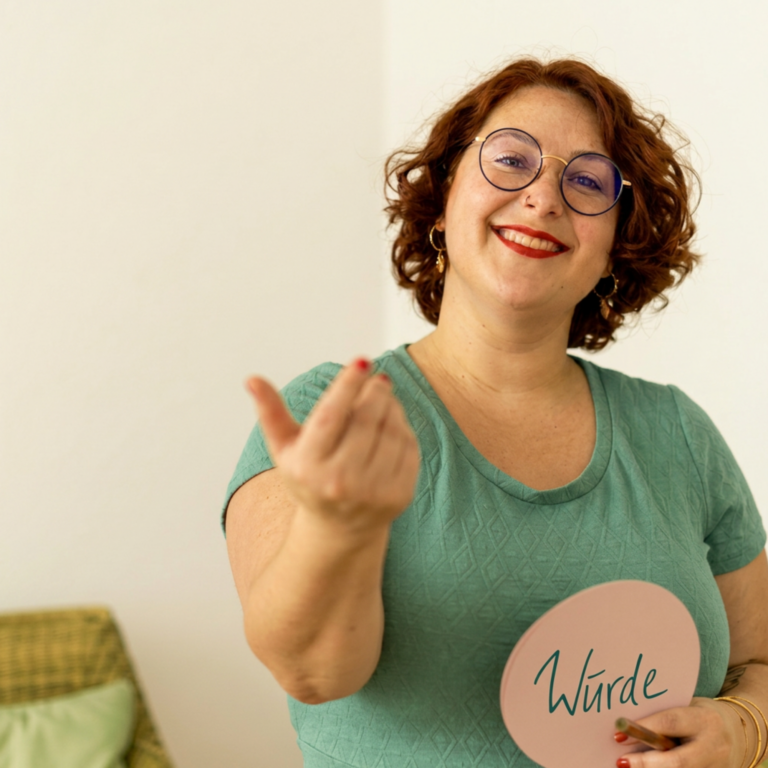 Inna Zeitler lächelt und hält ein Schild mit dem Wort Würde in der Hand